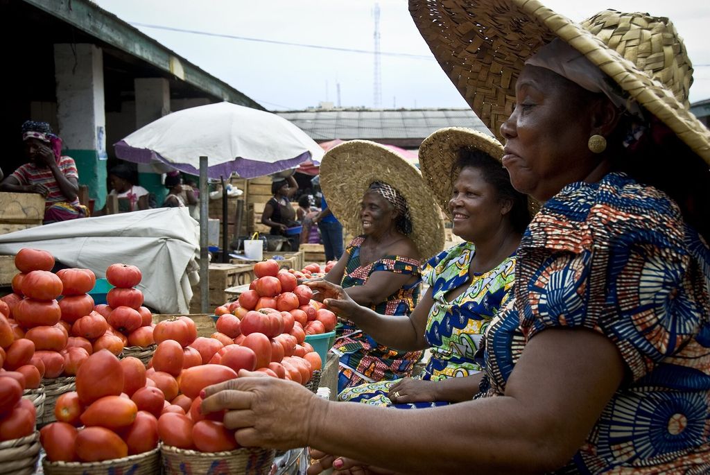 Tomato sellers in wide straw hats at the main market in Accra, Ghana