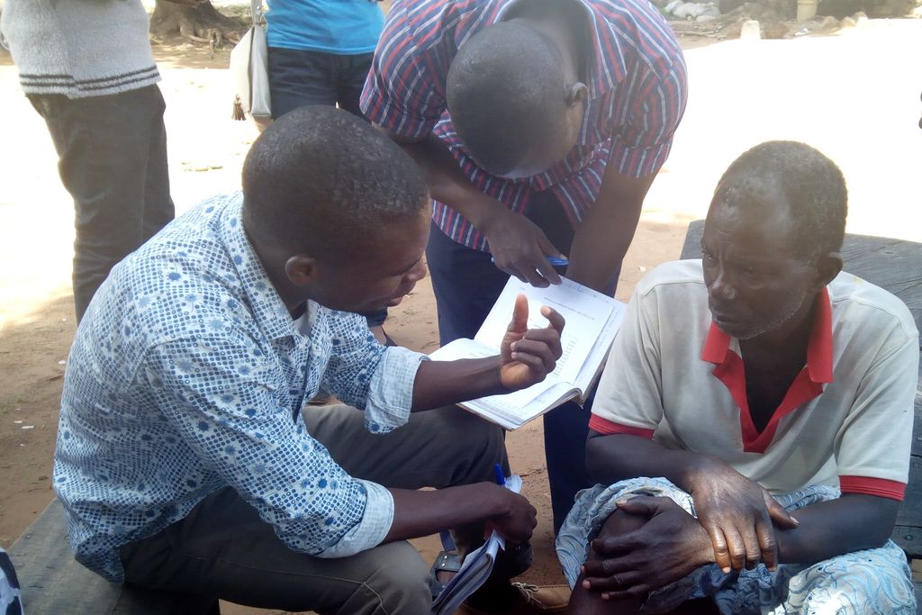Nigeria (Benue State): agriculture students with a questionnaire talk with a farmer about farming innovations, seated on a village bench
