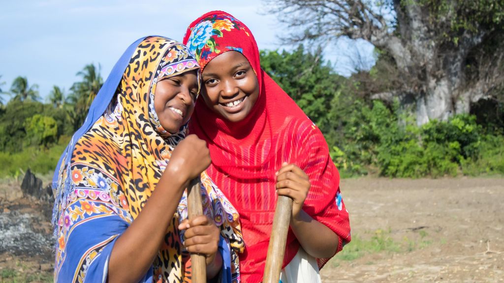 Two young women from a farmer group holding hoes after a training session in Pemba, Tanzania