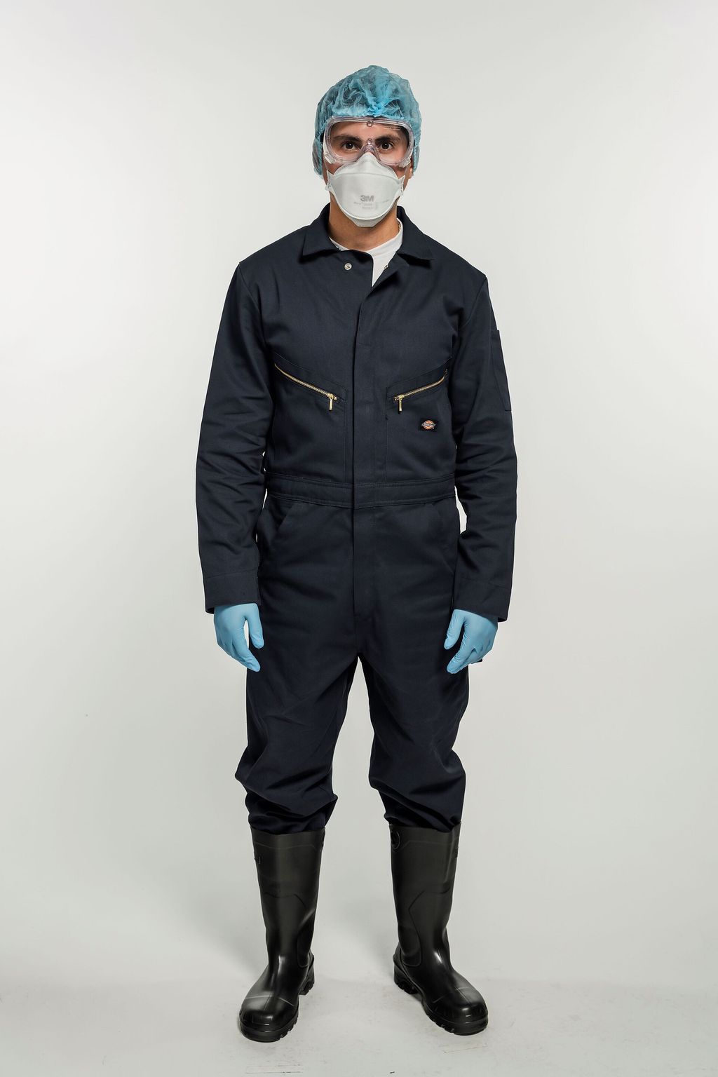 A person wearing a coverall, gloves, a respirator mask, safety goggles and boots